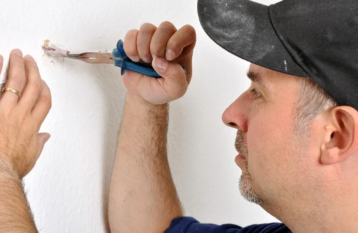 Person entfernt Dübel mit Zange